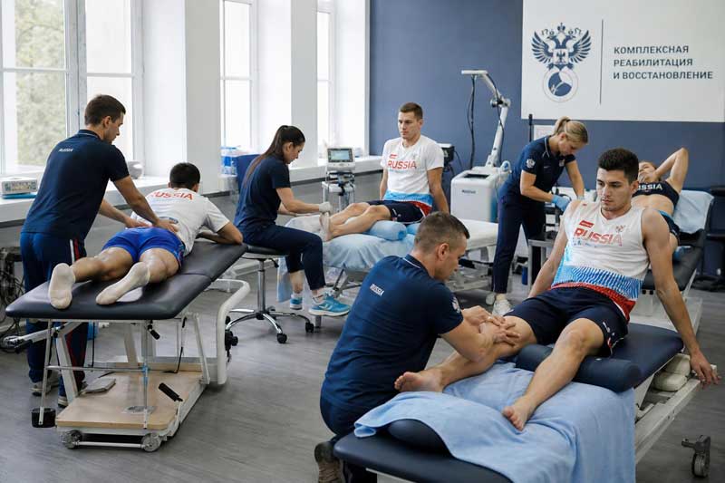 Группа спортсменов российской сборной проходит комплексную физиотерапию после интенсивной тренировки в медицинском центре